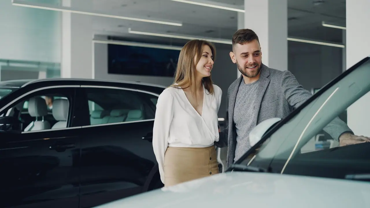 A couple looking over a car at a dealership