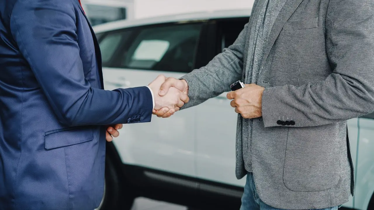A handshake beside a white SUV